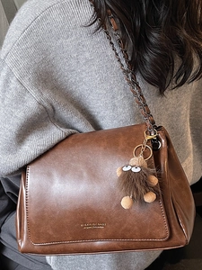 Large dark brown leather shoulder bag with gold chain strap and cute plush doll pendant