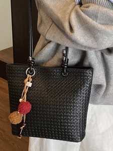 Minimalist black woven tote bag with shoulder straps and colorful decorative charm