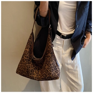 Detail of the large leopard print tote bag with brown straps styled with a striped suit
