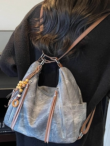 Gray vintage tote bag with brown straps and wooden bead tassel shown on a model