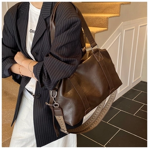 Detail of a large brown PU leather tote bag with an ethnic style woven shoulder strap