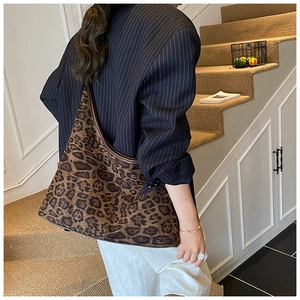 Detailed close-up of large leopard print tote bag with brown leather trim and texture