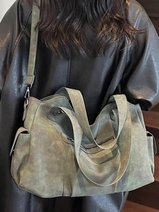 Grande borsa tote retrò verde in pelle opaca indossata da una modella in stile chic