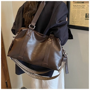 Detail view of large brown faux leather tote bag with ethnic style woven shoulder strap