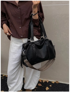 Detail of matte black Boston bag with textured wide strap and silver metal hardware