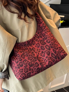 Large red and black leopard print hobo tote bag worn with a stylish trench coat