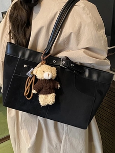 Large black patchwork tote bag with buckle detail and plush bear charm for daily commute