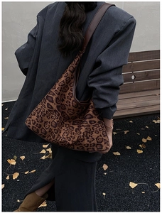 Detail of leopard print hobo tote bag with brown leather strap in an autumn park setting