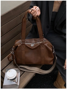 Detail of soft brown PU leather Boston bag with vintage woven strap and silver hardware