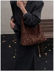 Detailed close-up of a large leopard print tote bag with brown leather straps for autumn fashion