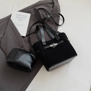 Detail view of black faux suede bucket bag with matching pouch and metal buckle on office blazer
