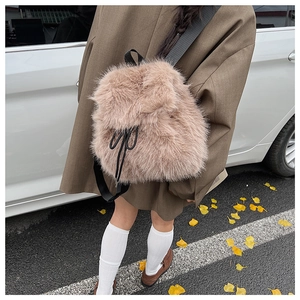Détail d'un sac à dos en peluche beige avec cordon noir dans un décor d'automne