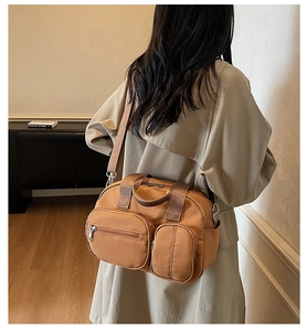 Detail of caramel nylon crossbody bag featuring multiple functional zipper pockets and straps