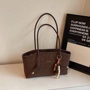 Close-up of dark brown tote bag featuring matte suede texture and beaded accessory detail