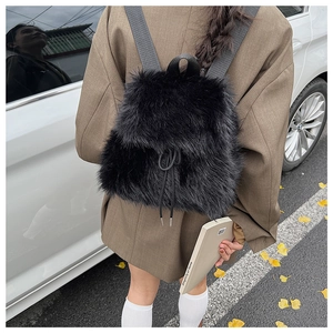 Vue détaillée d'un sac à dos en peluche noire avec cordon de serrage porté par un mannequin