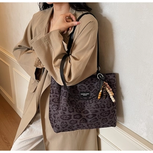 Detail of leopard print tote bag featuring wooden beaded tassel and logo patch