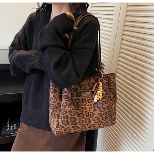 Close-up of leopard print tote bag with leather logo patch and wooden bead charm
