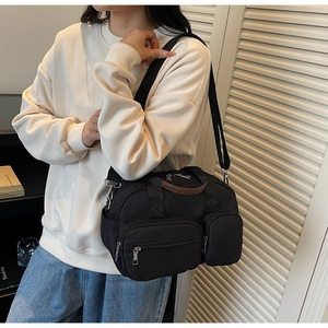 Detail showing high-density black nylon fabric with multiple zip pockets and brown trim