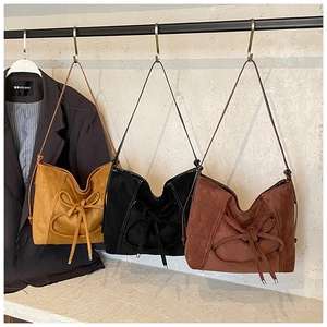 Détail de sacs cabas en daim avec de grands nœuds en jaune, noir et marron rouge