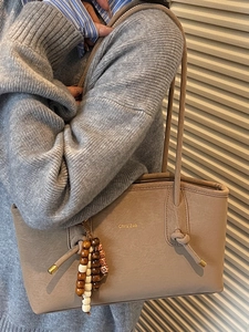 Minimalist beige leather tote bag with ethnic beaded tassel and long shoulder straps