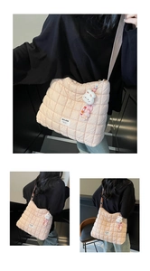 Detailed shot of pink quilted crossbody cloud bag with rabbit charm and nylon texture