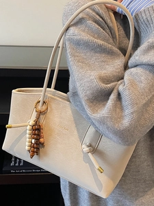 Minimalist cream leather tote bag with vintage wood bead charm and gold lettering