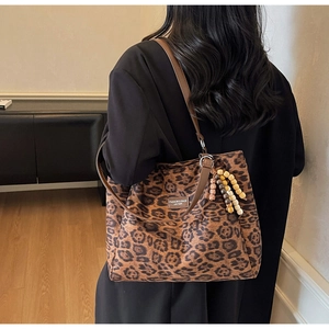 Detailed back view of leopard print suede tote bag with brown leather straps on a model