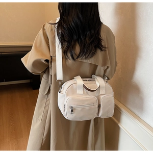 Close-up of beige multi-pocket travel bag worn with a stylish khaki trench coat