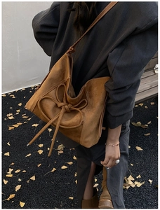 Détail du sac en daim caramel avec nœud décoratif et bandoulière pour l'automne