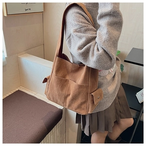 Détail du sac cabas en daim marron avec design multi-poches et fermoirs métalliques