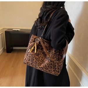 Detail of leopard print suede tote bag with leather strap and colorful tassel charm