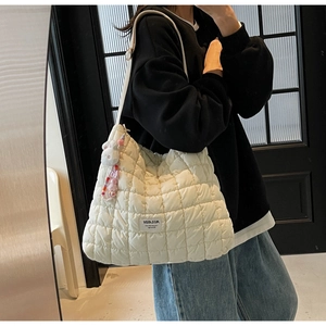 Detailed view of white quilted cloud bag with cute rabbit pendant on a female model