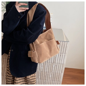 Détail d'un grand sac cabas en daim marron avec poches latérales à rabat sur un mannequin