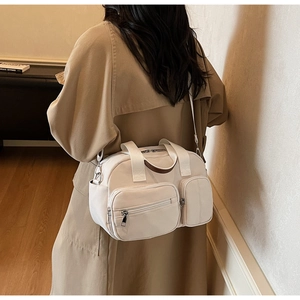 Detail view of cream nylon crossbody bag with dual zip pockets and adjustable strap