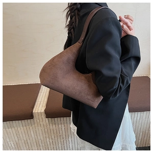 Detailed side view of a vintage dark brown suede hobo bag on a model's shoulder