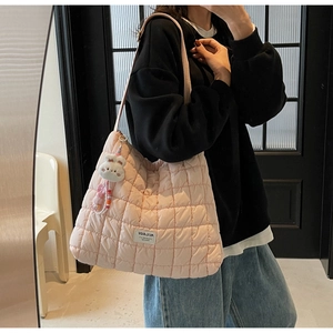 Detail of light pink quilted tote bag with cute rabbit charm and soft cloud texture