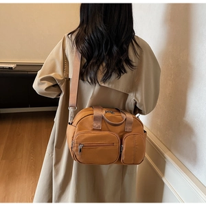 Detail of camel nylon crossbody bag with double front zip pockets and wide shoulder strap