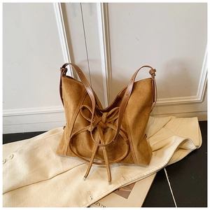 Gros plan du sac cabas en daim caramel avec un grand nœud décoratif et une bandoulière