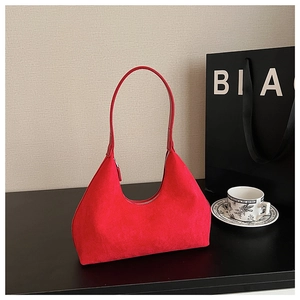 Detailed view of the red suede hobo bag with zipper and shoulder strap in a city setting