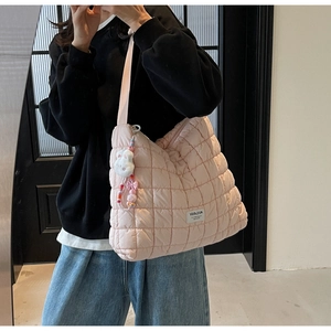Detail of light pink quilted cloud bag with plush rabbit charm and branded logo tag