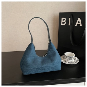 Detail view of deep blue suede crescent bag featuring smooth matte texture and sleek zipper