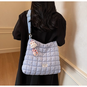 Detail of light blue quilted crossbody bag featuring a cute white bunny plush pendant