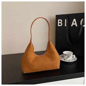 Brown suede half-moon underarm bag on a table with an elegant afternoon tea setup