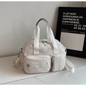 Detail of white large capacity tote bag with brown leather handles and side pockets