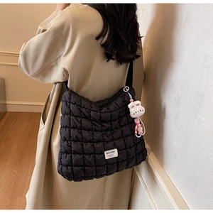 Detail of black quilted cloud bag featuring white logo tag and cute rabbit plush charm