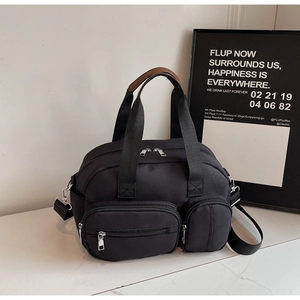 Detail view of the black multi-pocket tote bag with brown leather handles and silver hardware