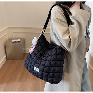 Detail of black quilted cloud bag with plush bunny charm and beaded accessory decoration