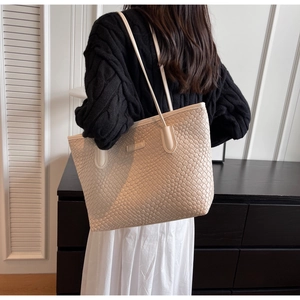 Detailed view of large off-white woven tote bag on shoulder for daily commute