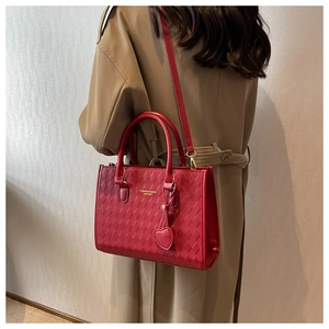 Detail of red quilted PU leather handbag with heart charm and golden fashion lettering