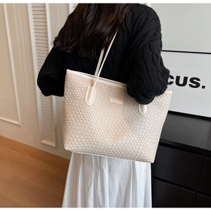 Detail view of cream white woven tote bag showing premium leather texture and large capacity